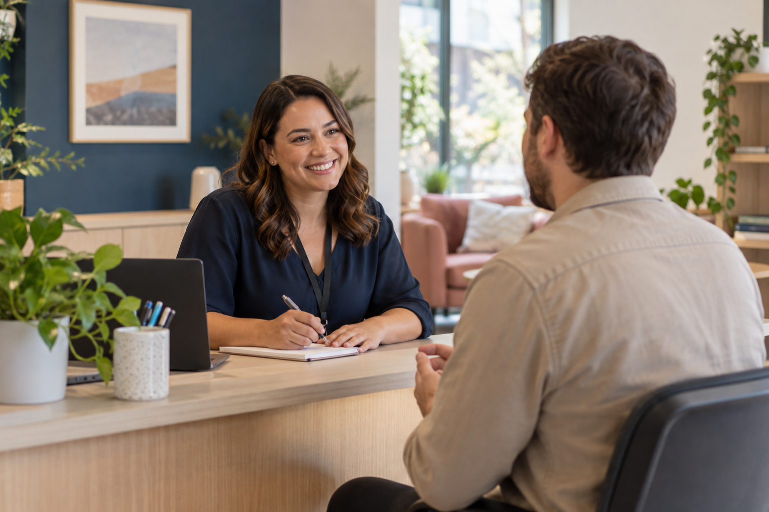 A friendly team member speaking with an adult visitor in a bright, accessible community office