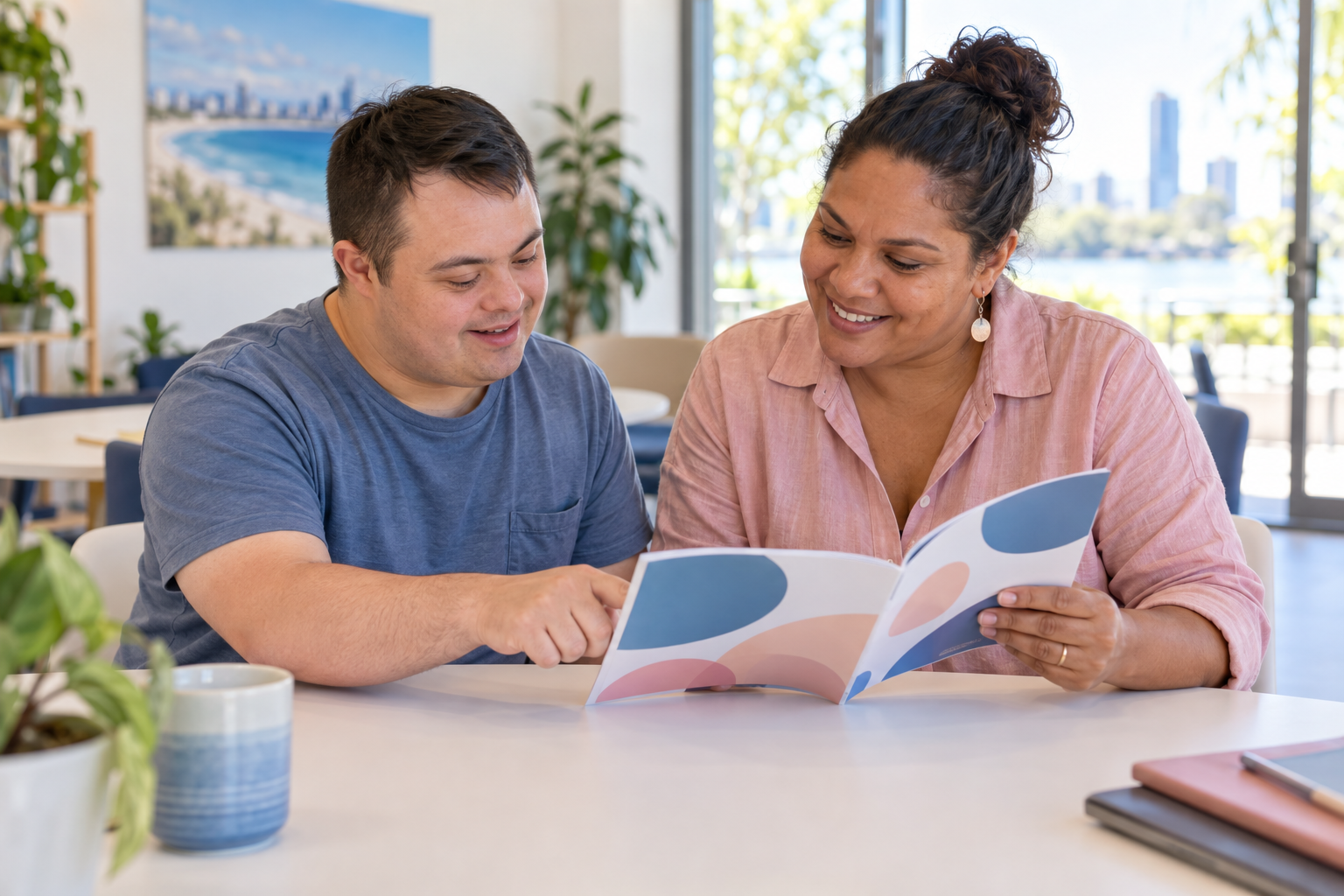 An adult and a support worker reviewing an easy-to-read information booklet together at a table.